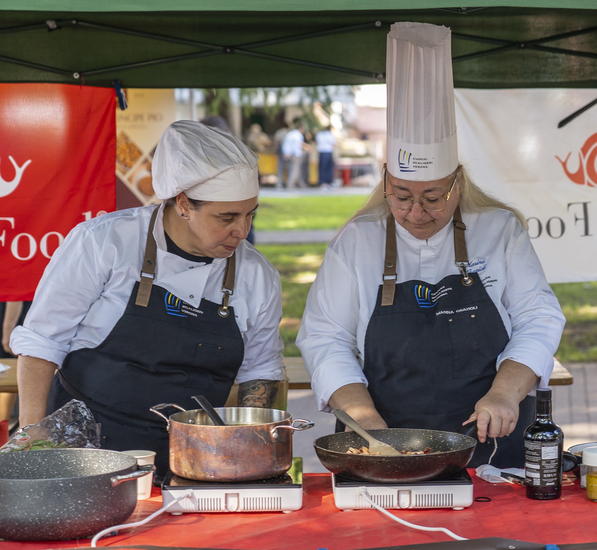 Cuoche ai fornelli e presentatore durante il cooking show al mercato